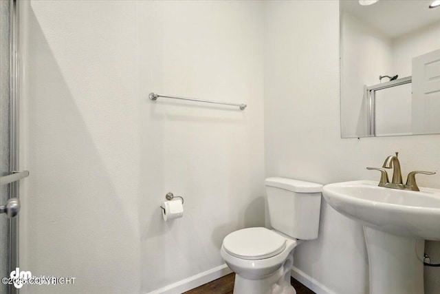 6744 Bogle Bluff Dr, Wasilla, AK 99623 - half bath with baseboards, toilet, a sink, and wood finished floors