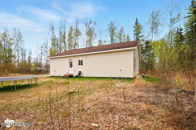 6744 Bogle Bluff Dr, Wasilla, AK 99623 - rear view of property with a trampoline and a yard