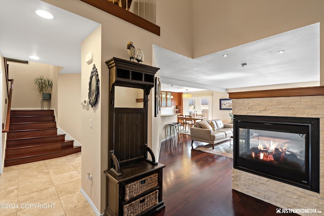 entryway featuring stairway, a stone fireplace, baseboards, light wood-style flooring, and recessed lighting