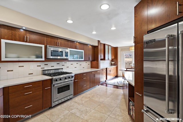 kitchen featuring high quality appliances, decorative backsplash, recessed lighting, and light tile patterned floors