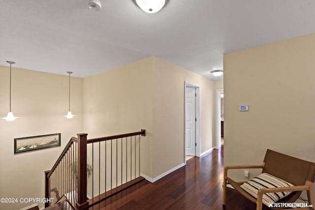 hallway featuring wood finished floors, an upstairs landing, and baseboards