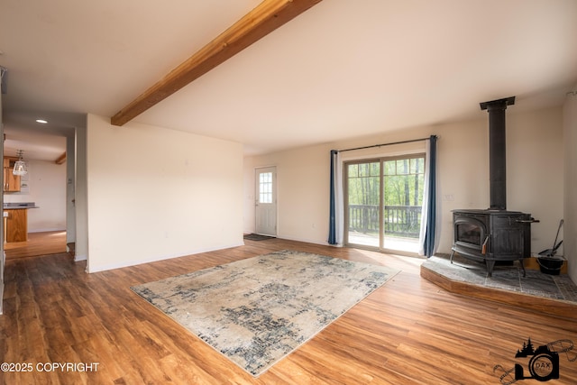 13333 E Constitution Dr, Palmer, AK 99645 - living room with beamed ceiling, a wood stove, wood finished floors, and baseboards