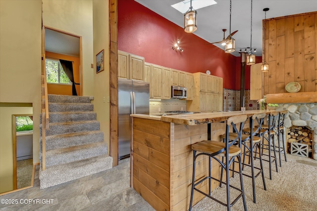 26266 Vallihi Cir, Eagle River, AK 99577 - kitchen with stainless steel appliances, a skylight, light brown cabinets, a towering ceiling, and backsplash