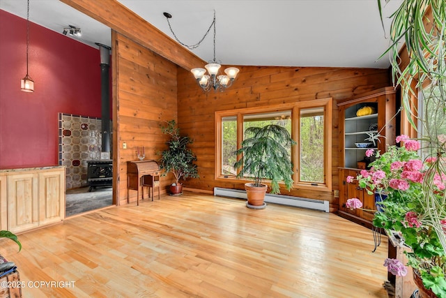 26266 Vallihi Cir, Eagle River, AK 99577 - unfurnished dining area with wood finished floors, wood walls, a wood stove, a baseboard heating unit, and a chandelier