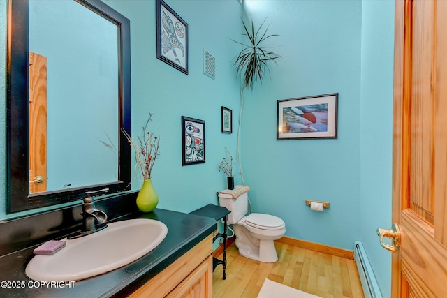 26266 Vallihi Cir, Eagle River, AK 99577 - bathroom with a baseboard heating unit, wood finished floors, toilet, vanity, and baseboards