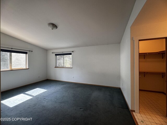 33325 Vinewood Ln, Seward, AK 99664 - unfurnished bedroom featuring vaulted ceiling, multiple windows, light colored carpet, a spacious closet, and baseboards