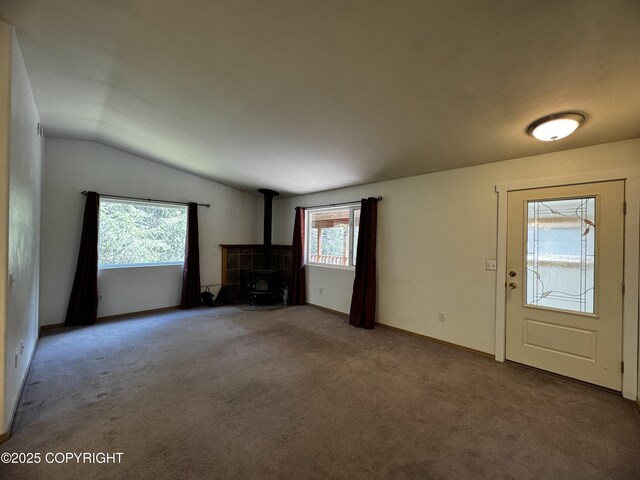 33325 Vinewood Ln, Seward, AK 99664 - unfurnished living room with a wood stove, vaulted ceiling, carpet flooring, and baseboards