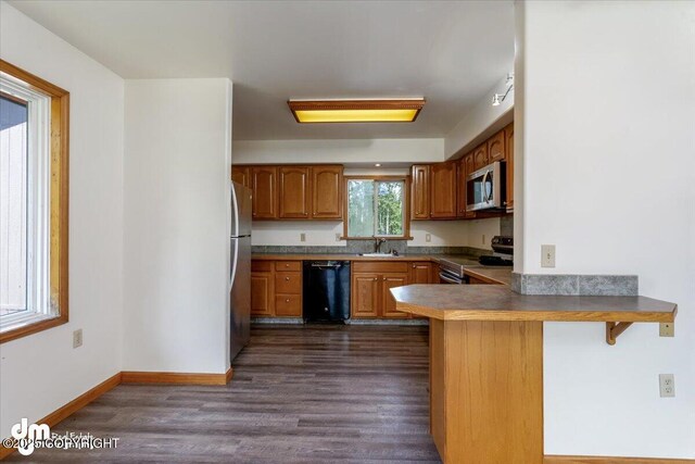 14184 W Jojoba Rd, Big Lake, AK 99623 - kitchen featuring stainless steel appliances, a sink, a peninsula, brown cabinetry, and dark wood-style floors