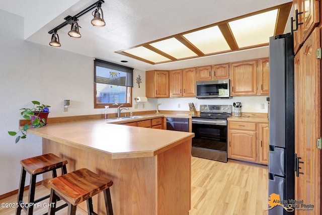 4230 Woronzof Dr # D, Anchorage, AK 99517 - kitchen featuring stainless steel appliances, a peninsula, a breakfast bar, a sink, and light countertops