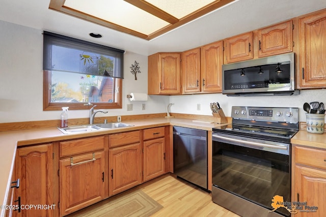 4230 Woronzof Dr # D, Anchorage, AK 99517 - kitchen featuring appliances with stainless steel finishes, a sink, light countertops, light wood finished floors, and brown cabinetry