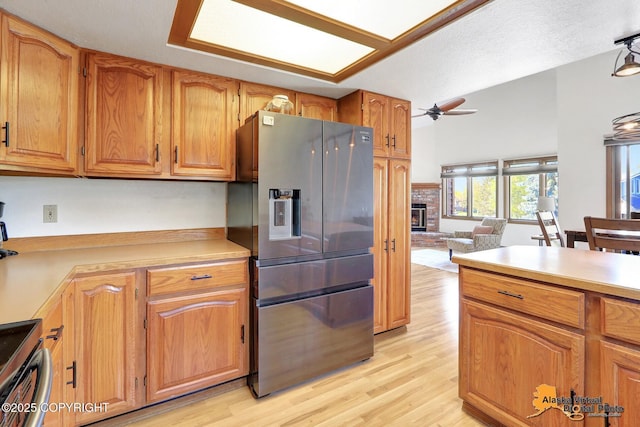 4230 Woronzof Dr # D, Anchorage, AK 99517 - kitchen featuring appliances with stainless steel finishes, a ceiling fan, light wood finished floors, light countertops, and a brick fireplace