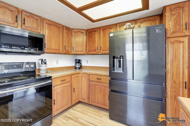 4230 Woronzof Dr # D, Anchorage, AK 99517 - kitchen featuring stainless steel appliances, light countertops, brown cabinets, and light wood-style flooring