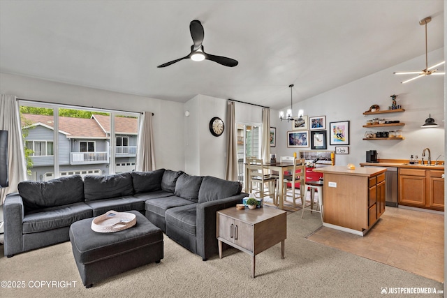 living area with ceiling fan, vaulted ceiling, a chandelier, and light colored carpet