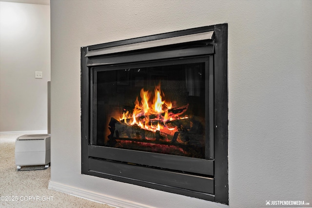 detailed view of baseboards and a lit fireplace