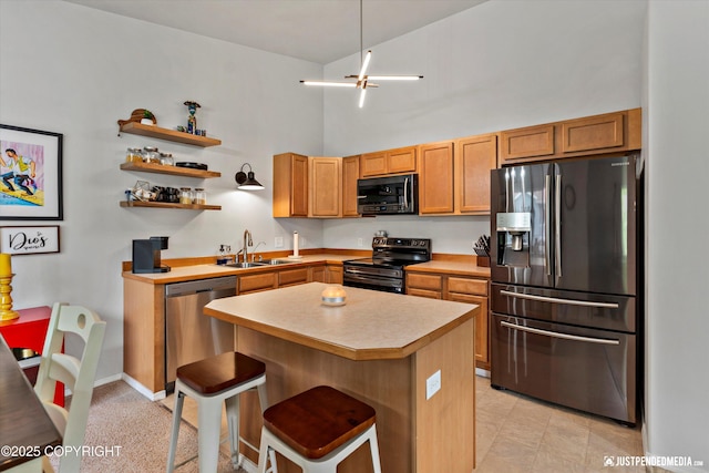 kitchen featuring stainless steel appliances, a sink, light countertops, a kitchen island, and a breakfast bar area