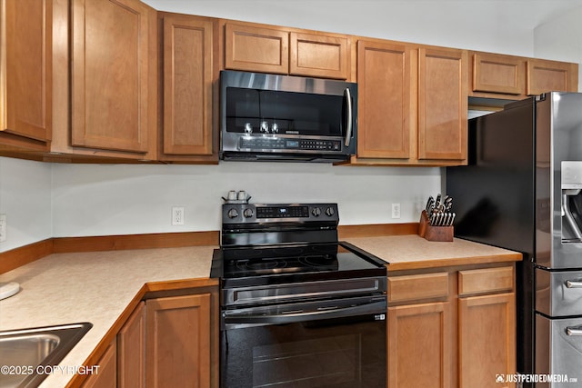 kitchen with appliances with stainless steel finishes, light countertops, brown cabinetry, and a sink