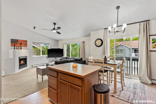kitchen featuring lofted ceiling, a ceiling fan, a chandelier, brown cabinets, and a warm lit fireplace