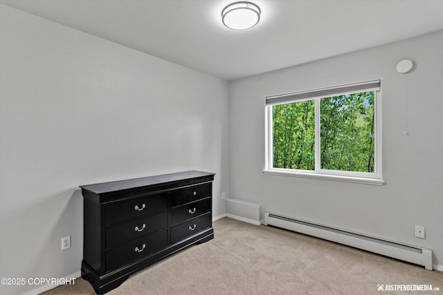 unfurnished bedroom with baseboard heating, carpet, and baseboards