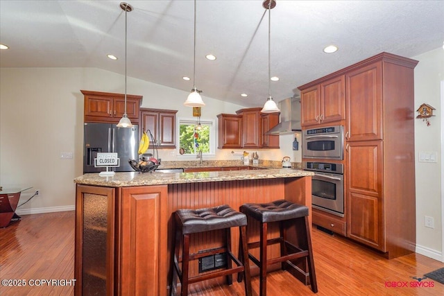 2750 E Whispering Woods Dr, Wasilla, AK 99654 - kitchen featuring appliances with stainless steel finishes, wall chimney range hood, lofted ceiling, light wood-style floors, and a center island
