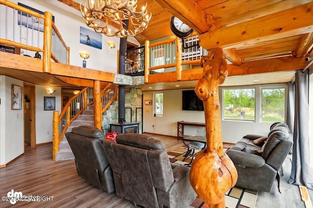 living area with stairs, a chandelier, wood finished floors, beam ceiling, and healthy amount of natural light