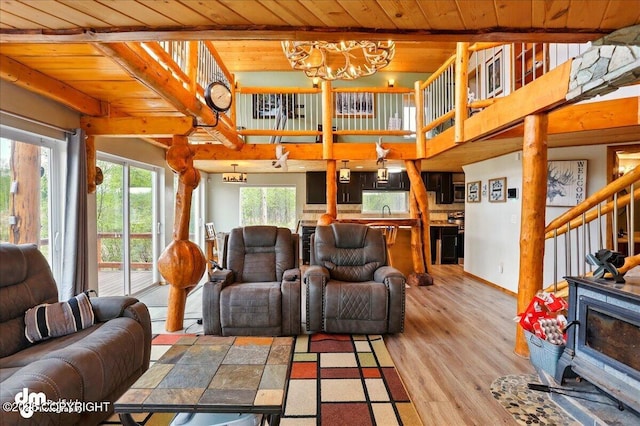 living area with wooden ceiling, a wood stove, a chandelier, beamed ceiling, and light wood finished floors