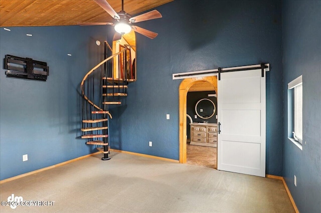 unfurnished living room featuring wood ceiling, a ceiling fan, a barn door, carpet, and stairs