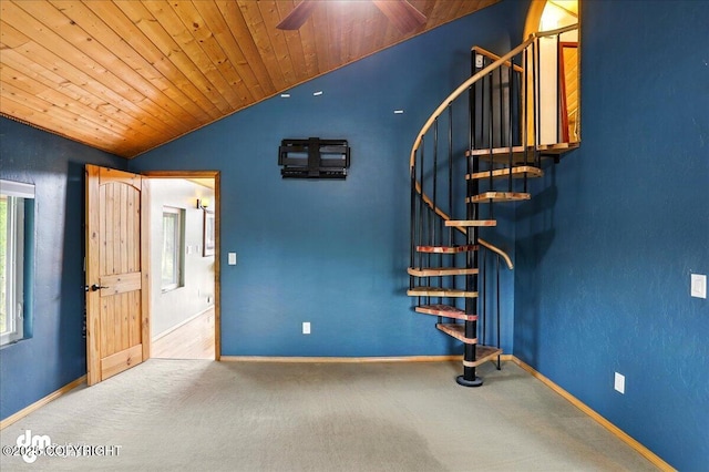 empty room featuring vaulted ceiling, stairs, baseboards, carpet flooring, and ceiling fan