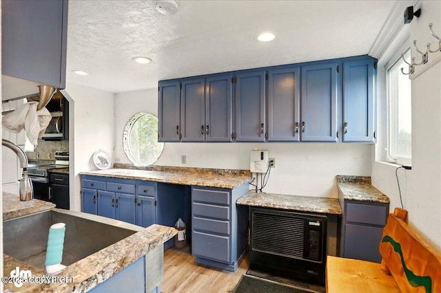 kitchen with blue cabinetry, stainless steel appliances, light wood-style floors, recessed lighting, and backsplash