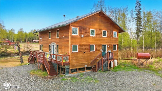 back of property with heating fuel, stairway, and a deck