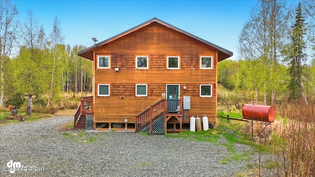 back of property with heating fuel and a wooded view