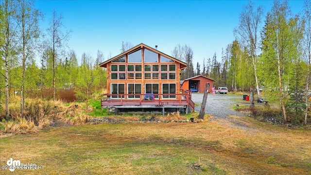 rear view of house featuring an outbuilding, driveway, and a lawn