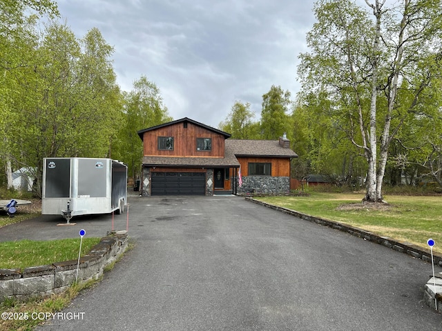 21675 Sheltering Spruce Loop, Chugiak, AK 99567 - view of front of house featuring a garage, driveway, stone siding, and a front yard