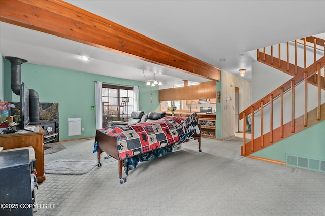 carpeted living area featuring stairway, a sink, a wood stove, baseboards, and beam ceiling