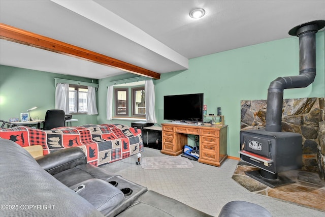 living area featuring a wood stove, carpet, and beamed ceiling