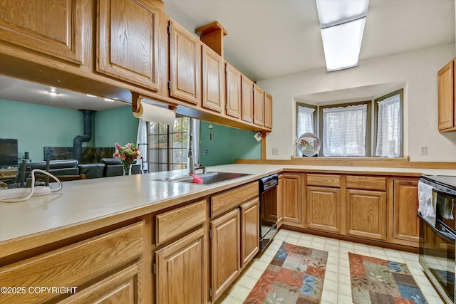 kitchen featuring black dishwasher, range with electric stovetop, light countertops, a sink, and brown cabinetry