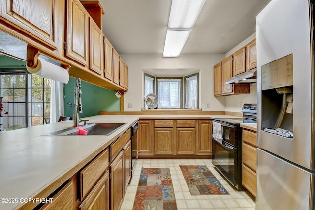 kitchen with black appliances, under cabinet range hood, a sink, light countertops, and healthy amount of natural light