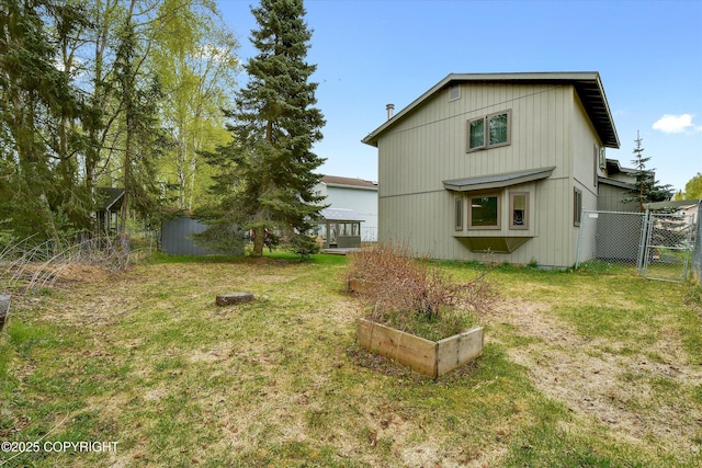 back of house with a garden and a gate