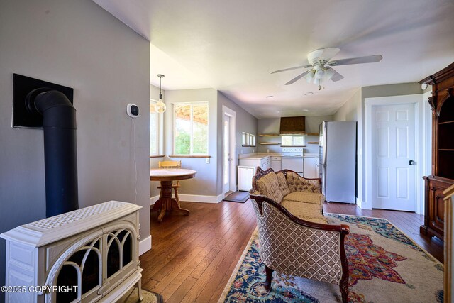 3625 W Hill Rd, Homer, AK 99603 - living room with ceiling fan, dark wood-style floors, baseboards, and a wood stove