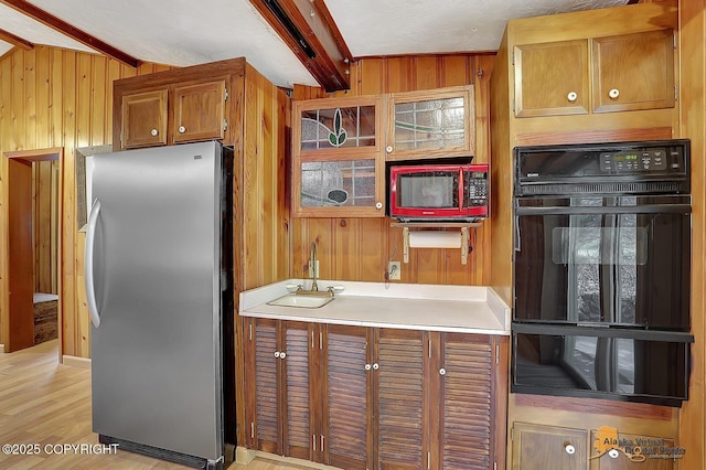 20811 Eagle River Rd, Eagle River, AK 99577 - kitchen with freestanding refrigerator, wood walls, a sink, beamed ceiling, and brown cabinetry
