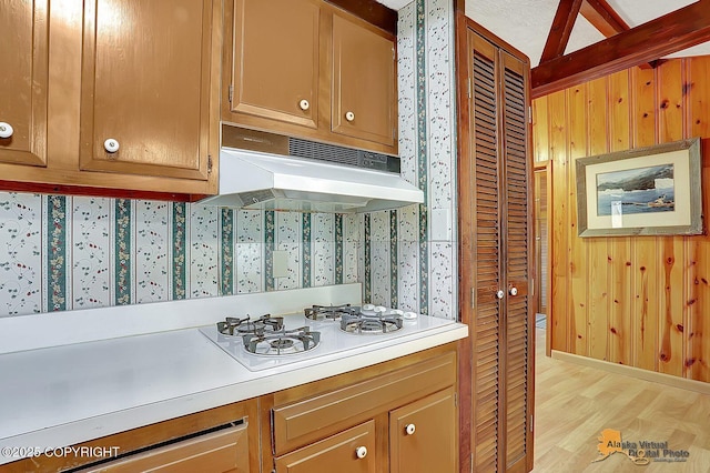 20811 Eagle River Rd, Eagle River, AK 99577 - kitchen featuring under cabinet range hood, white gas stovetop, light countertops, light wood-type flooring, and wooden walls