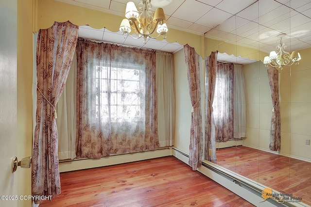 20811 Eagle River Rd, Eagle River, AK 99577 - spare room featuring a chandelier, wood-type flooring, ornamental molding, and a baseboard radiator
