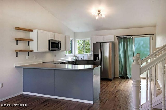kitchen with appliances with stainless steel finishes, open shelves, a peninsula, white cabinetry, and high vaulted ceiling