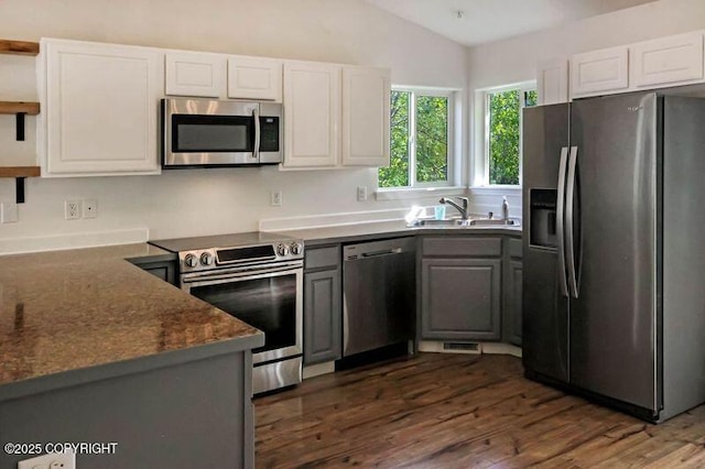kitchen featuring stainless steel appliances, a sink, open shelves, dark wood-style flooring, and white cabinetry