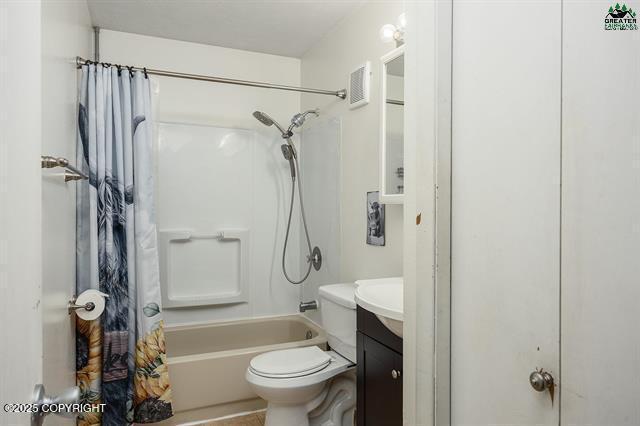full bathroom featuring vanity, shower / bath combination with curtain, and toilet