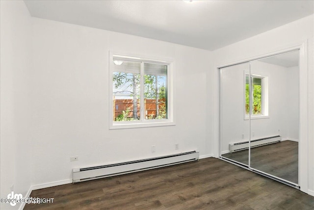 961 E Dellwood St, Wasilla, AK 99654 - unfurnished bedroom featuring a baseboard radiator, baseboard heating, multiple windows, and wood finished floors