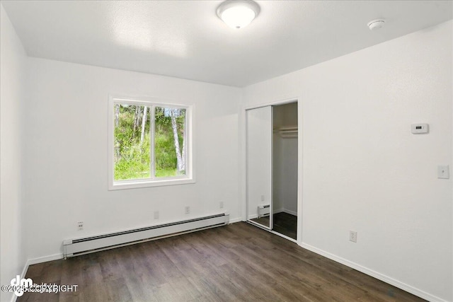 961 E Dellwood St, Wasilla, AK 99654 - unfurnished bedroom featuring a baseboard radiator, dark wood-type flooring, baseboards, and a closet
