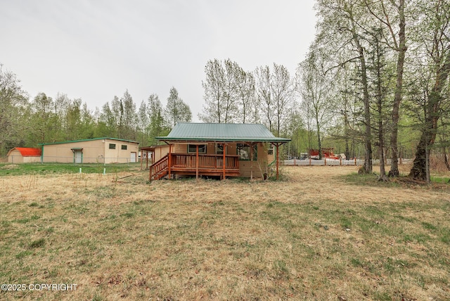 rear view of house with covered porch, metal roof, and a lawn