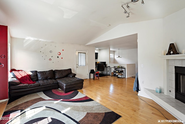 1957 Terrebonne Loop, Anchorage, AK 99502 - living area with light wood-style floors, track lighting, vaulted ceiling, a tiled fireplace, and a desk