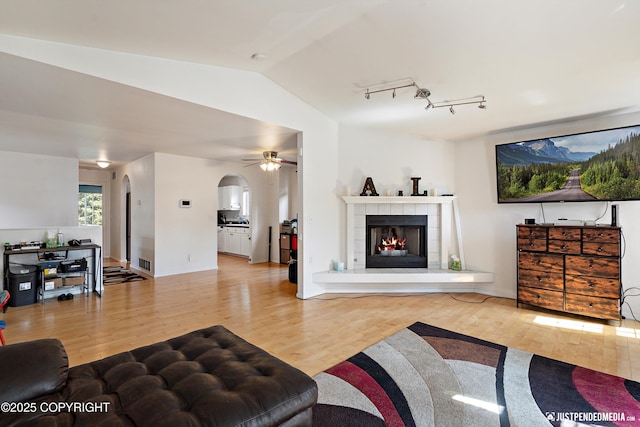 1957 Terrebonne Loop, Anchorage, AK 99502 - living room with arched walkways, wood finished floors, a ceiling fan, a tile fireplace, and vaulted ceiling