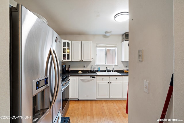 1957 Terrebonne Loop, Anchorage, AK 99502 - kitchen with appliances with stainless steel finishes, dark countertops, white cabinetry, light wood-style flooring, and glass insert cabinets